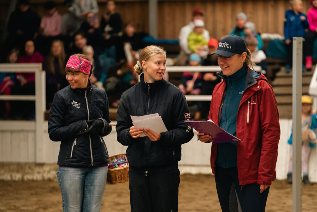 Kolme naista seisoo maneesissa katsomon edessä avoimien ovien päivänä
